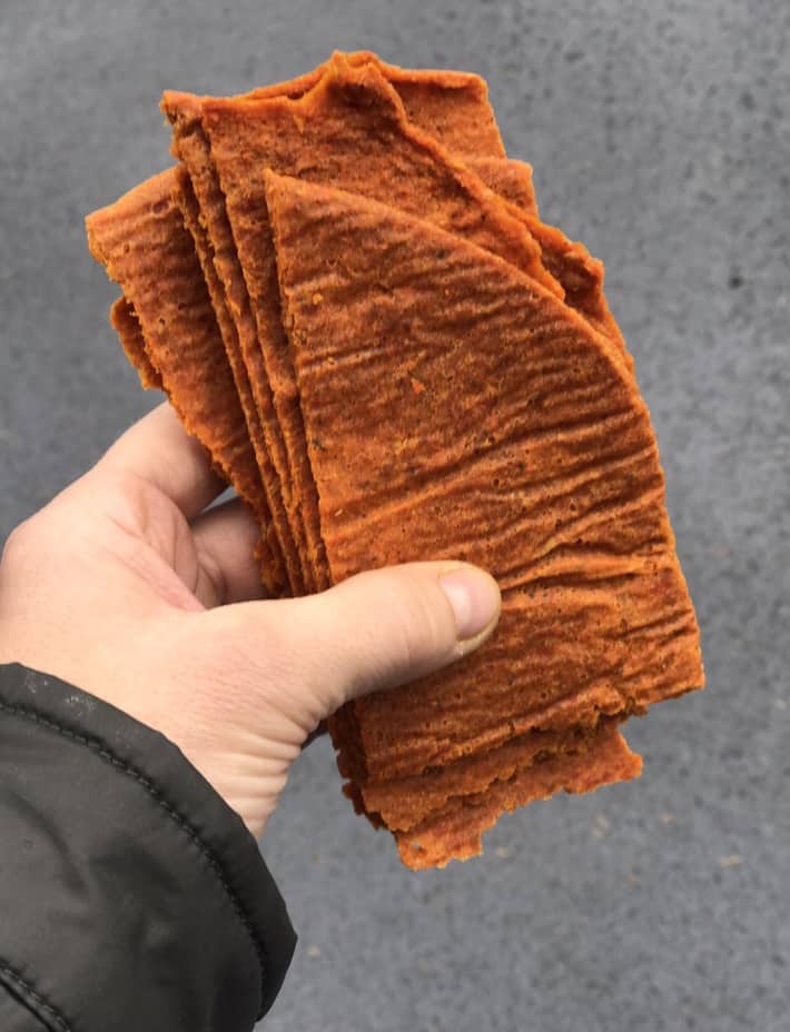 holding a stack of orange raw veggie bread