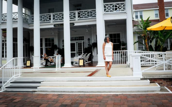 girl wearing a white shirt and white skirt and yellow shoes in front of a souther plantation