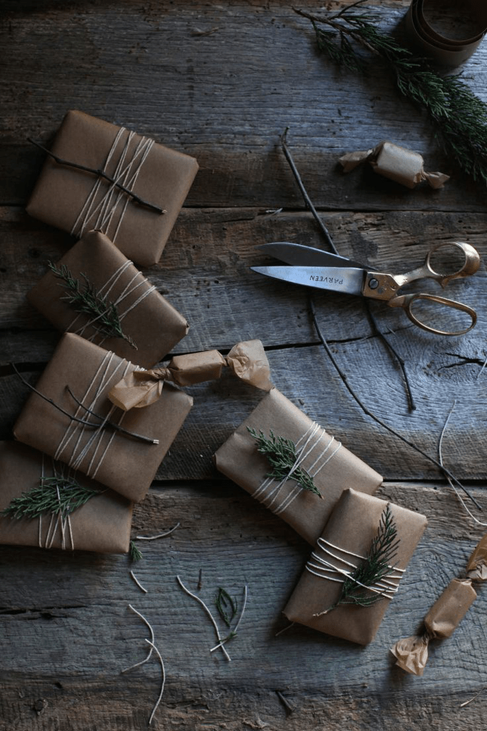 several gifts wrapped multiple times in twine and adorned with live foliage 