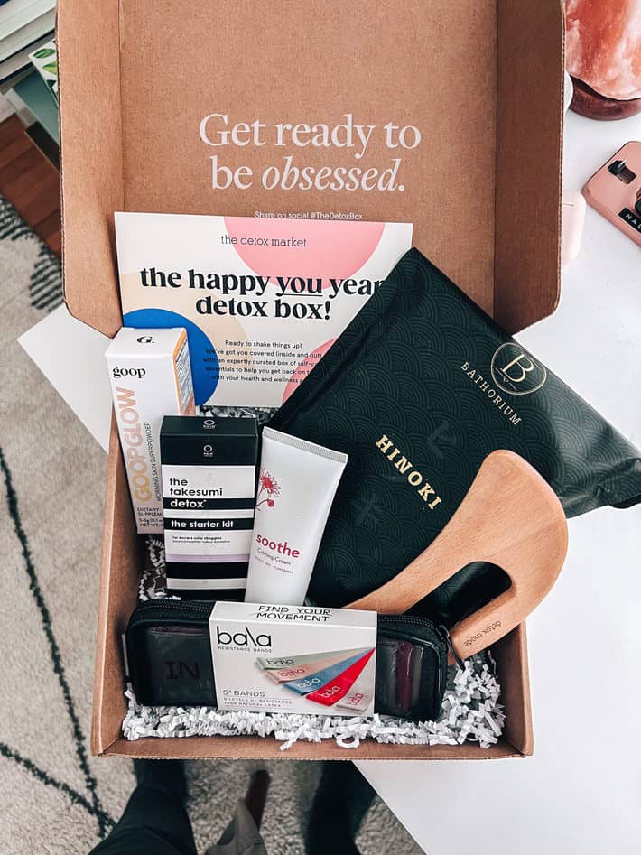 holding the January 2022 detox box with beauty and wellness products