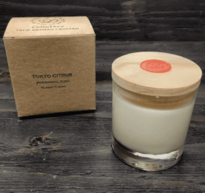 coconut wax candle with wooden lid placed next to its packaging