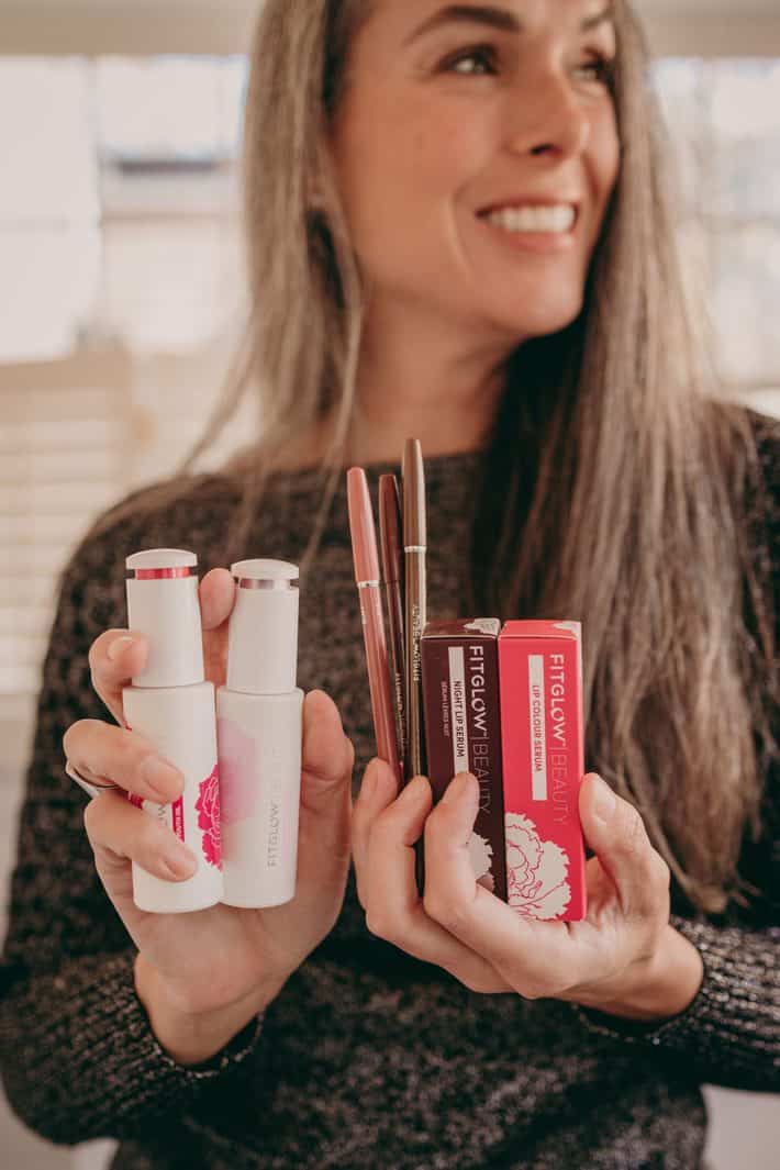 woman holding skincare and makeup products from Fitglow