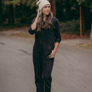 standing in the street wearing coveralls and a beanie