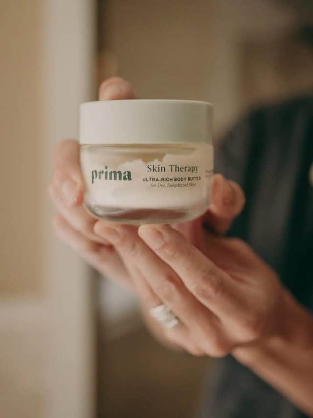 a woman holds up a tub of Prima's skin therapy 