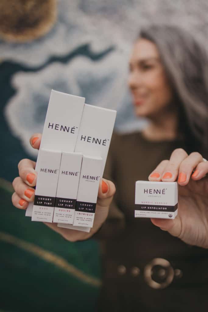 Lisa holding boxes of Henne Organics lip balm, luxury lip tints and lip exfoliator