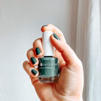 woman's hand holding a bottle of Dazzle Dry nontoxic nail polish in green
