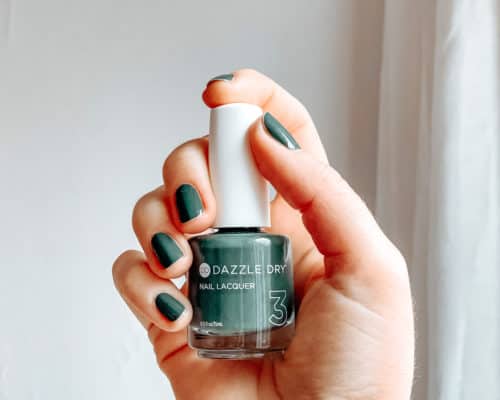 woman's hand holding a bottle of Dazzle Dry nontoxic nail polish in green