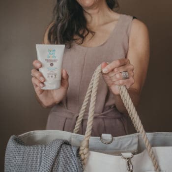 a woman holds a bag and a container of mineral bodyspf
