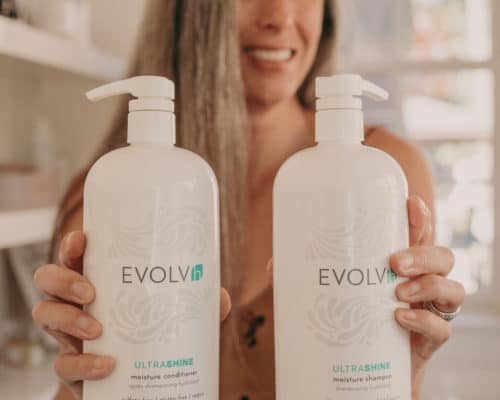 lisa holds two liter bottles of clean shampoo and conditioner from EVOLVh