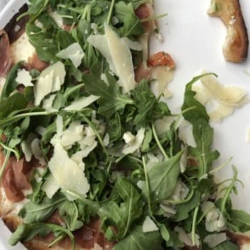 plate with pizza and arugula