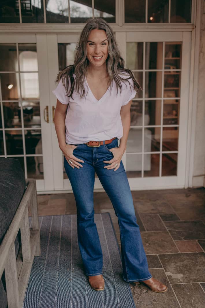 a smiling woman wearing a white t shirt and jeans 