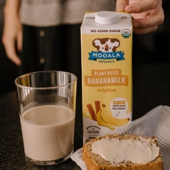 glass of bananamilk, banana bread and container of bananamilk sit on a counter