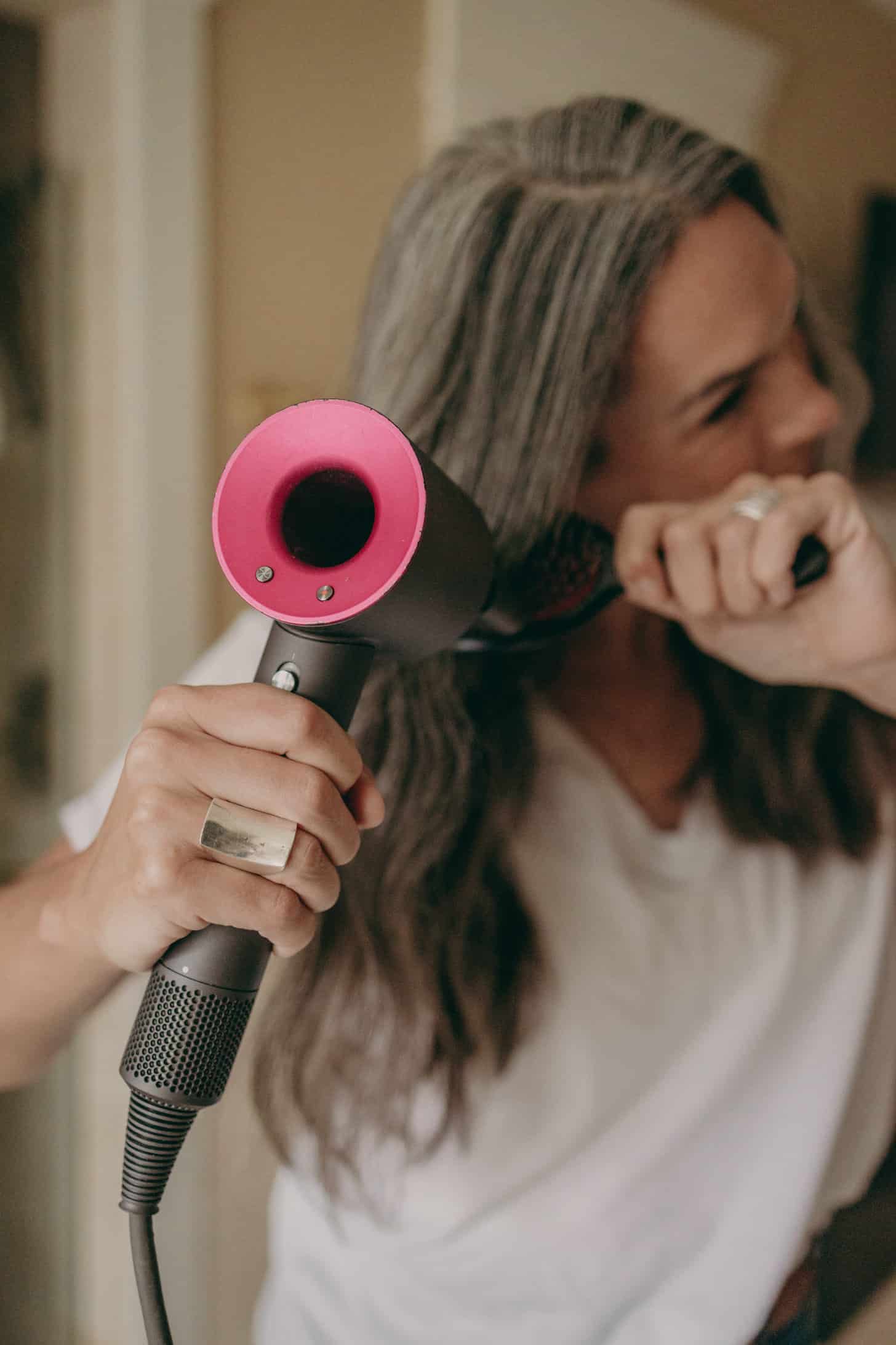 a woman blow dries her hair using a dyson blow dryer