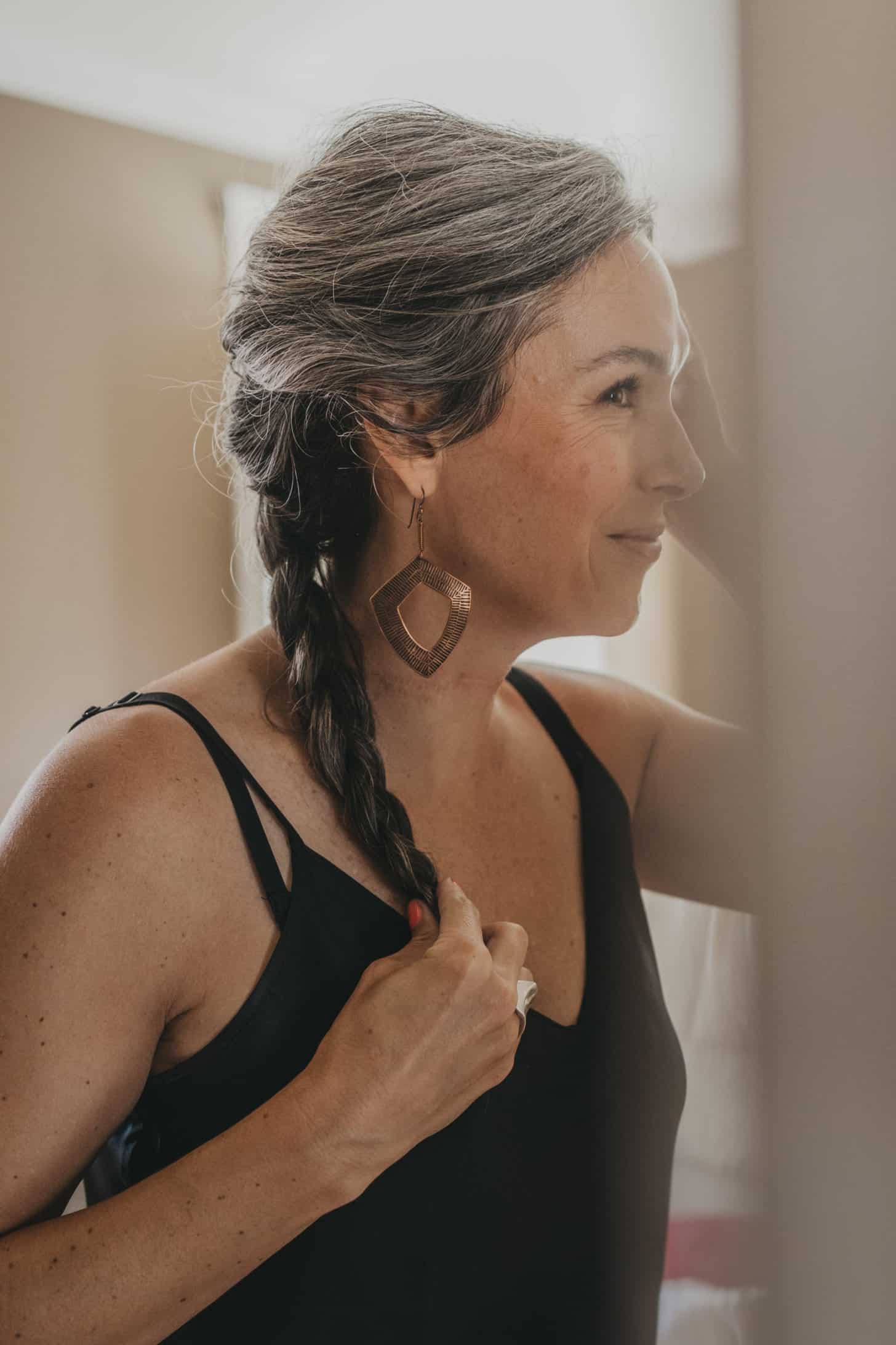 a woman with a long gray braid looks into the mirror