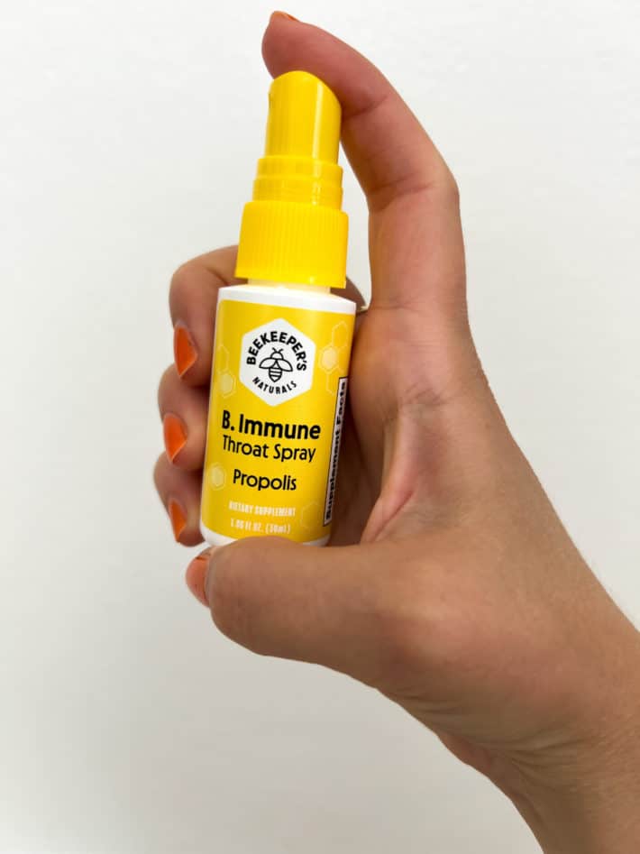 a woman holds a bottle of B. Immune Throat Spray by Propolis in her hand