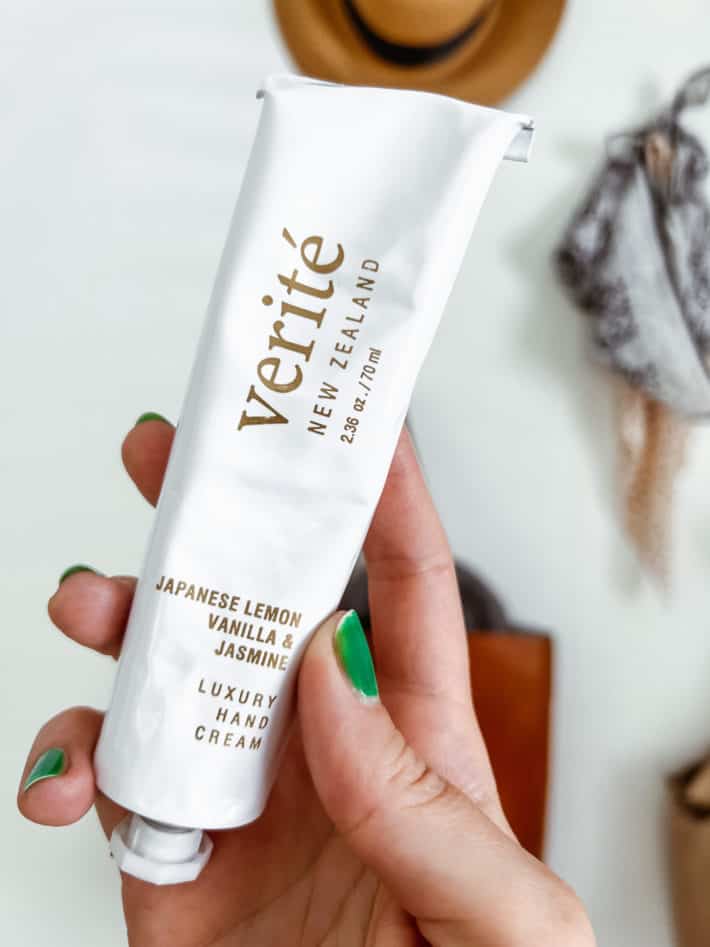 a tube of Verite Luxury Hand Cream is held in a hand with green painted fingernails