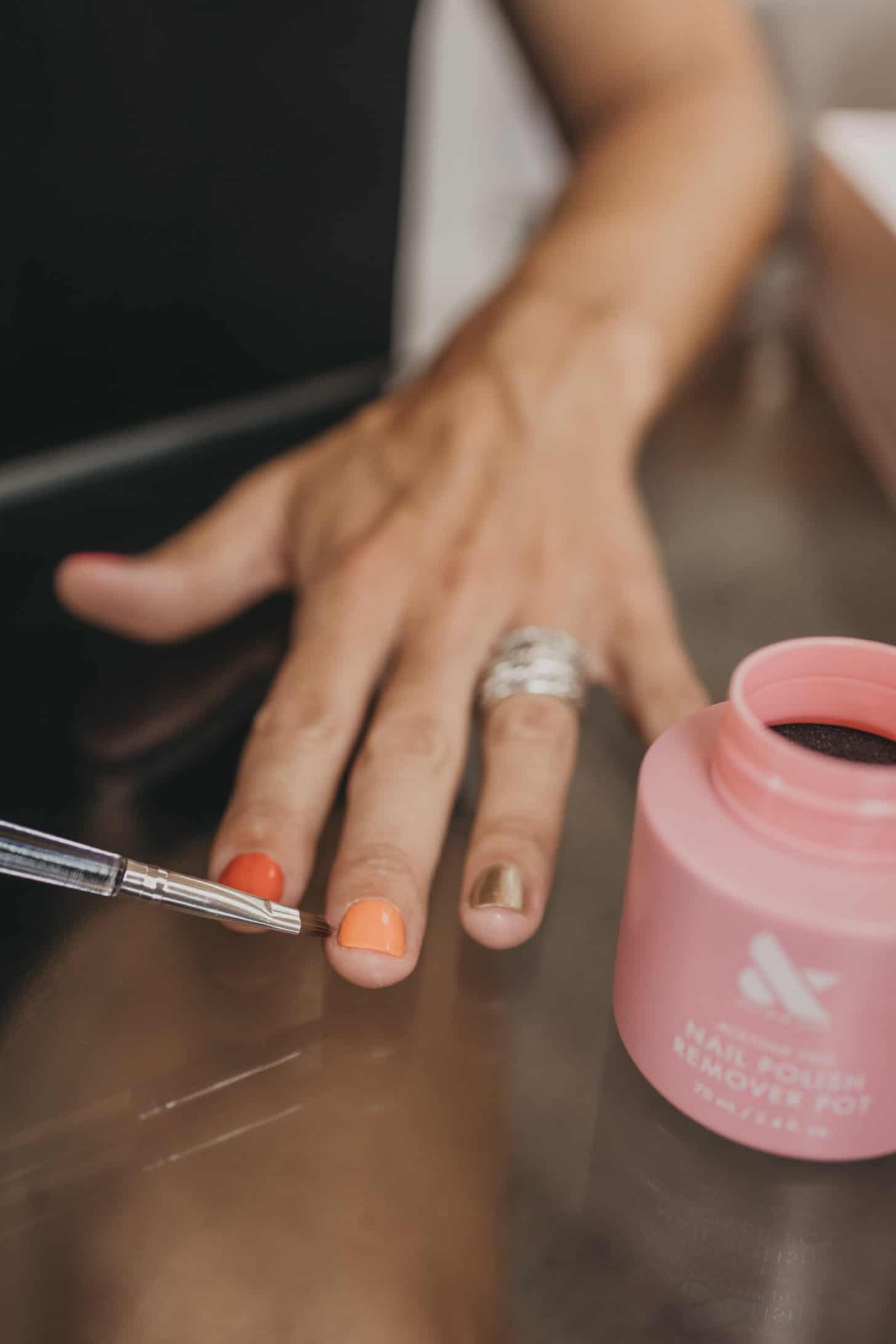 a woman removes her nail polish with olive and june products