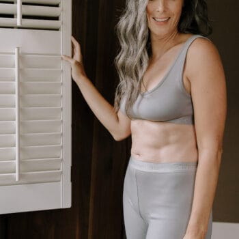 a woman stands near a window while wearing amreve biker shorts and a bralette