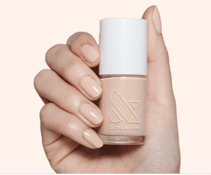a bottle of olive & june coffee milk nail polish held in a hand with nails painted the same color